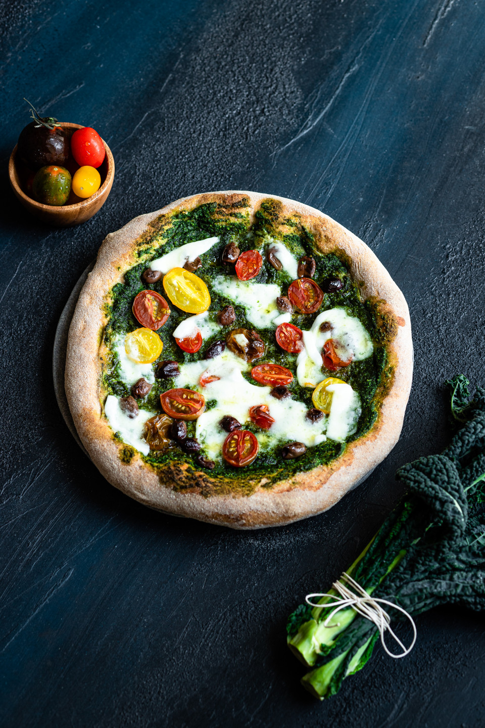 Pizza integrale con pesto di cavolo nero, pomodorini, olive taggiasche e mozzarella di bufala